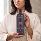 Adult woman holding Aveda Invati Advanced Thickening Conditioner, 1 L; styled AI lifestyle scene